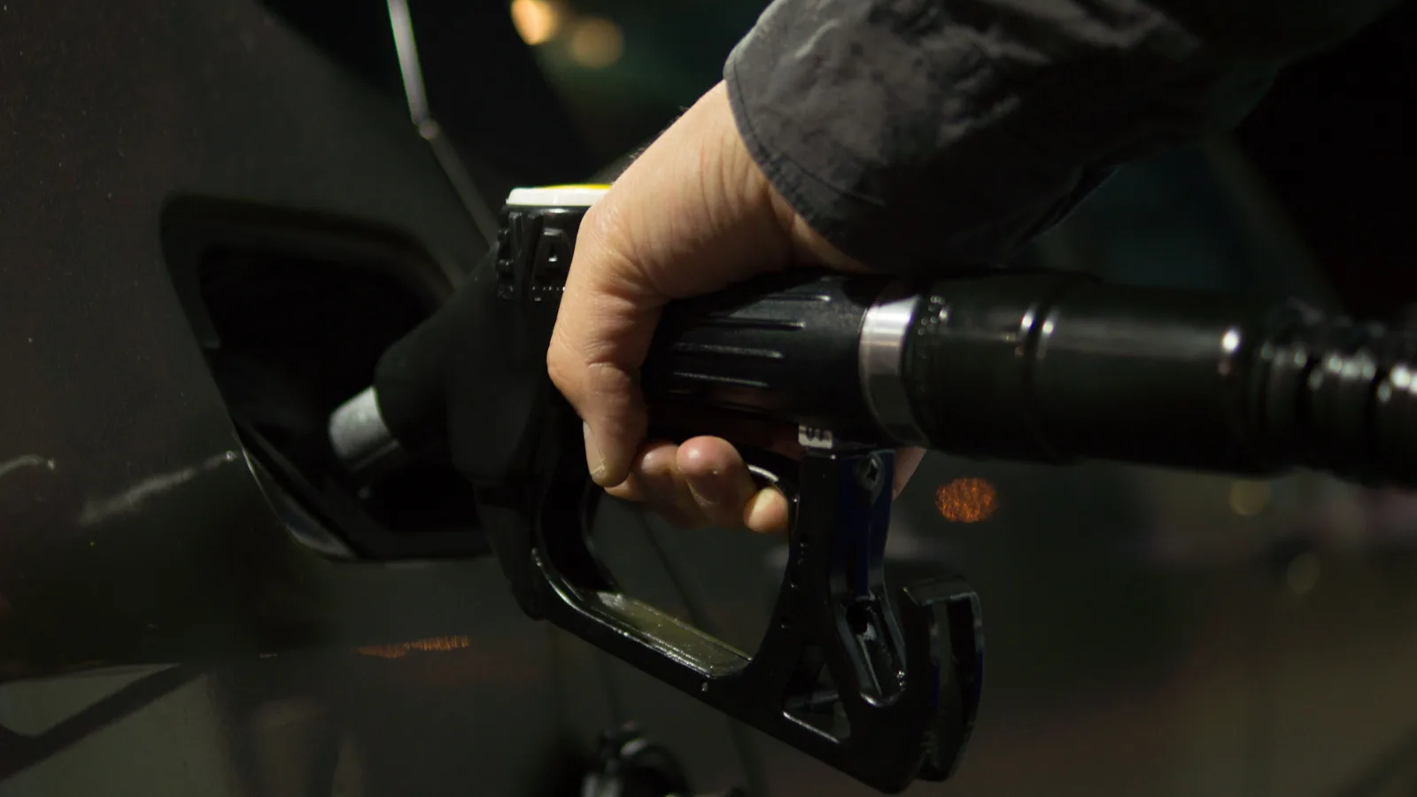 Green petrol pump nozzle filling a car at a service station