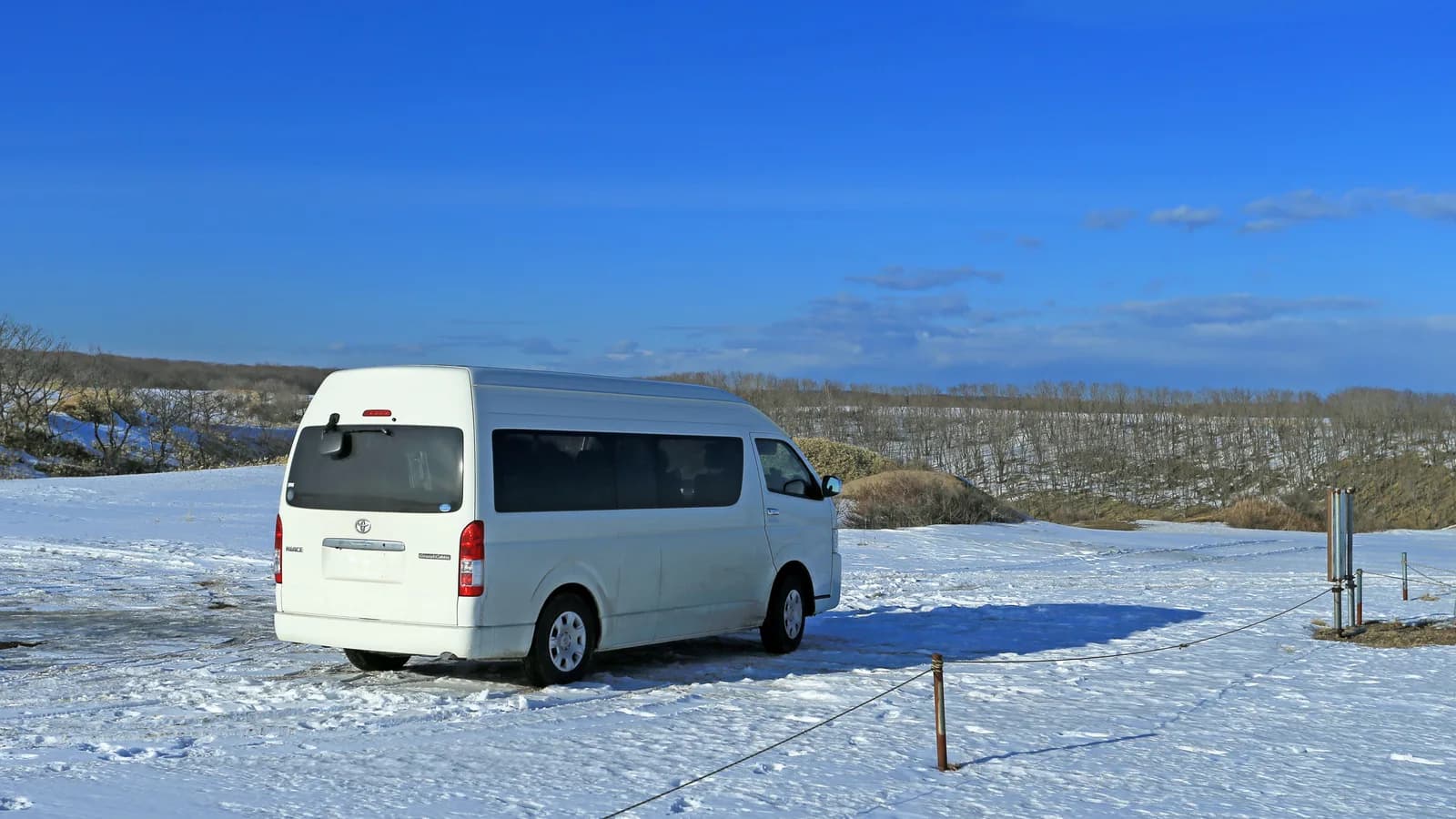 White Toyota HiAce Grand Cabin with Japanese badging parked in snow under a clear sky
