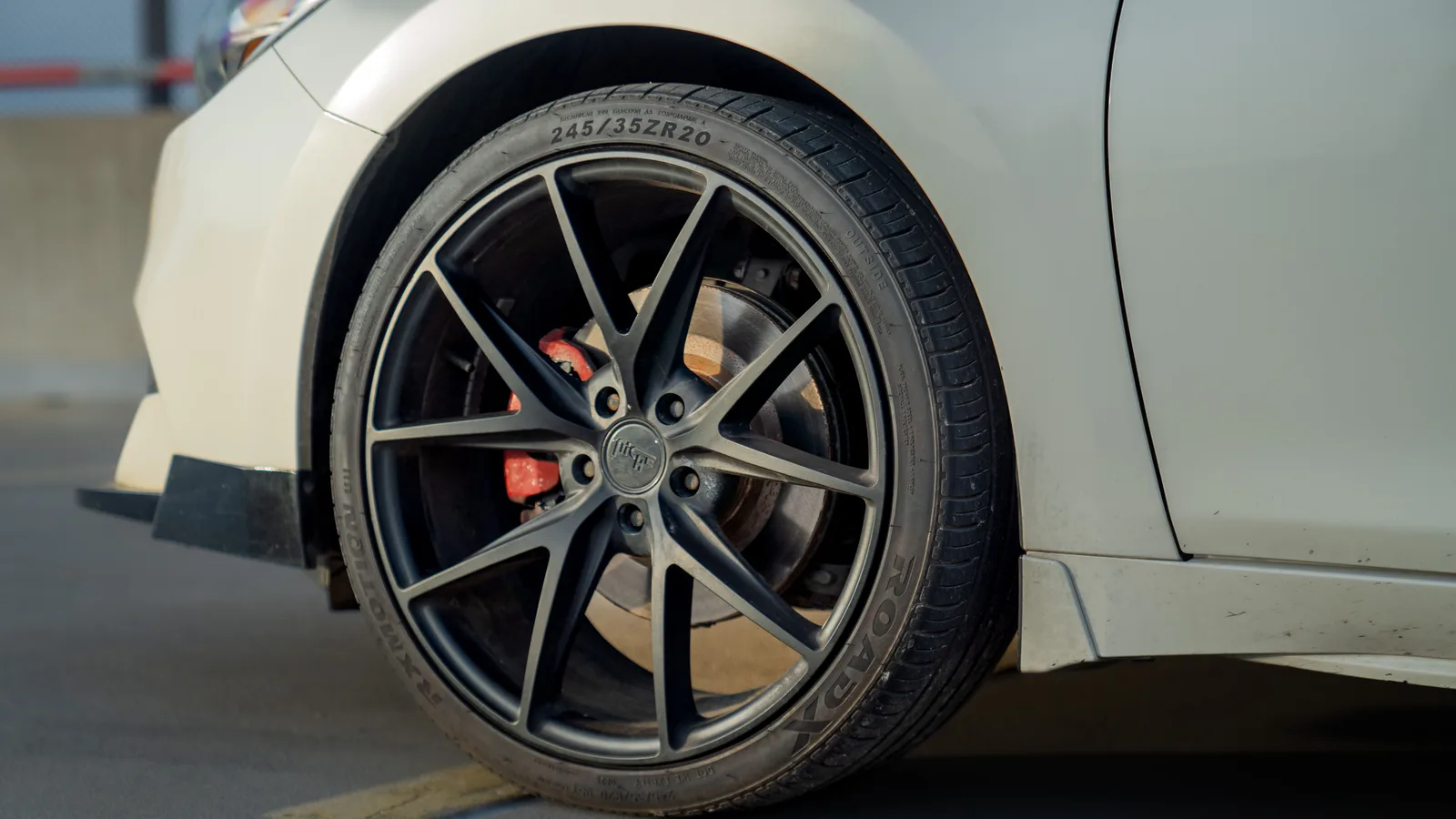 Close-up of an alloy wheel and tyre tread on a car parked on a city street