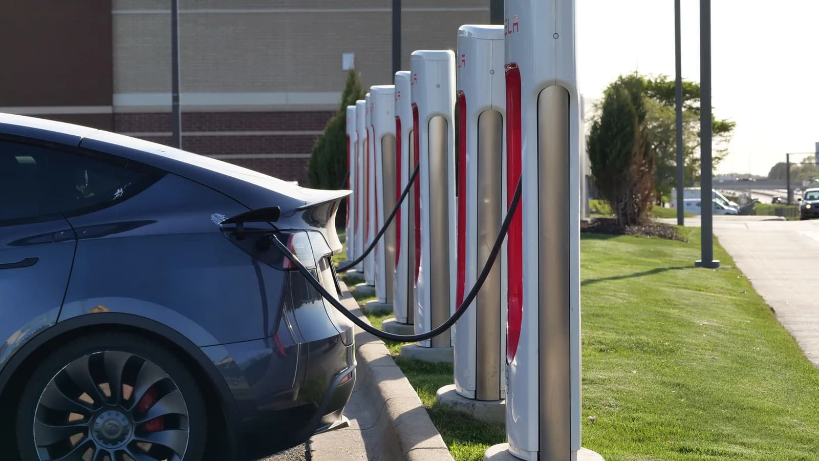 A dark electric car connected to one of several fast-charging stalls