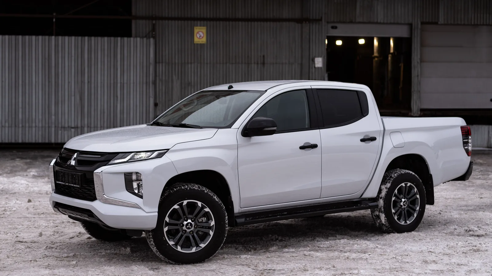 White Mitsubishi Triton dual-cab ute parked outside an industrial building