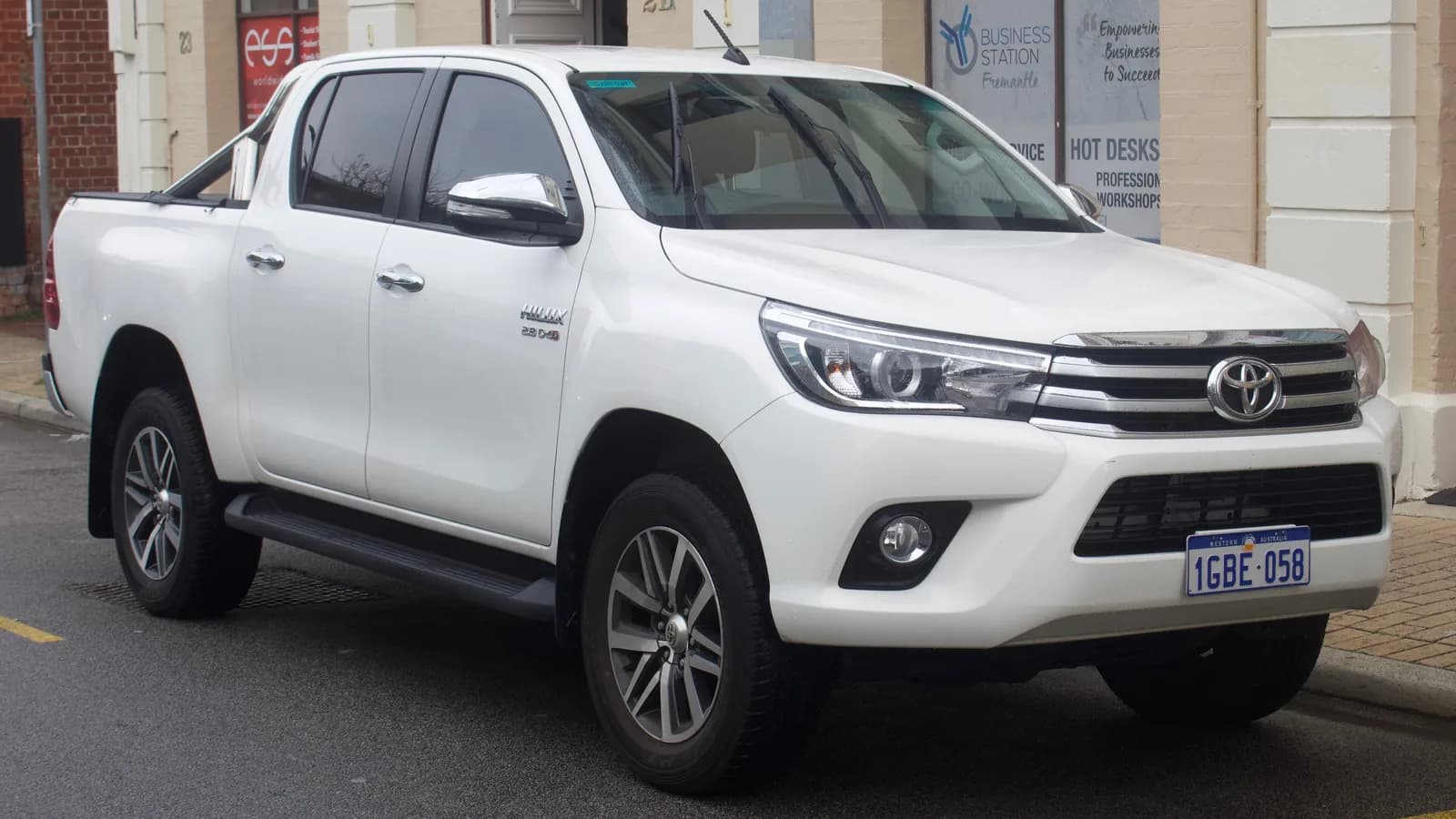 White Toyota HiLux dual-cab ute parked at the kerb outside a business