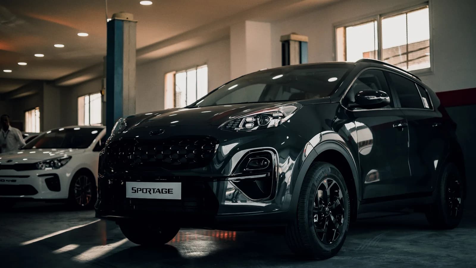 A dark grey small SUV parked on a polished dealership showroom floor with another car behind it