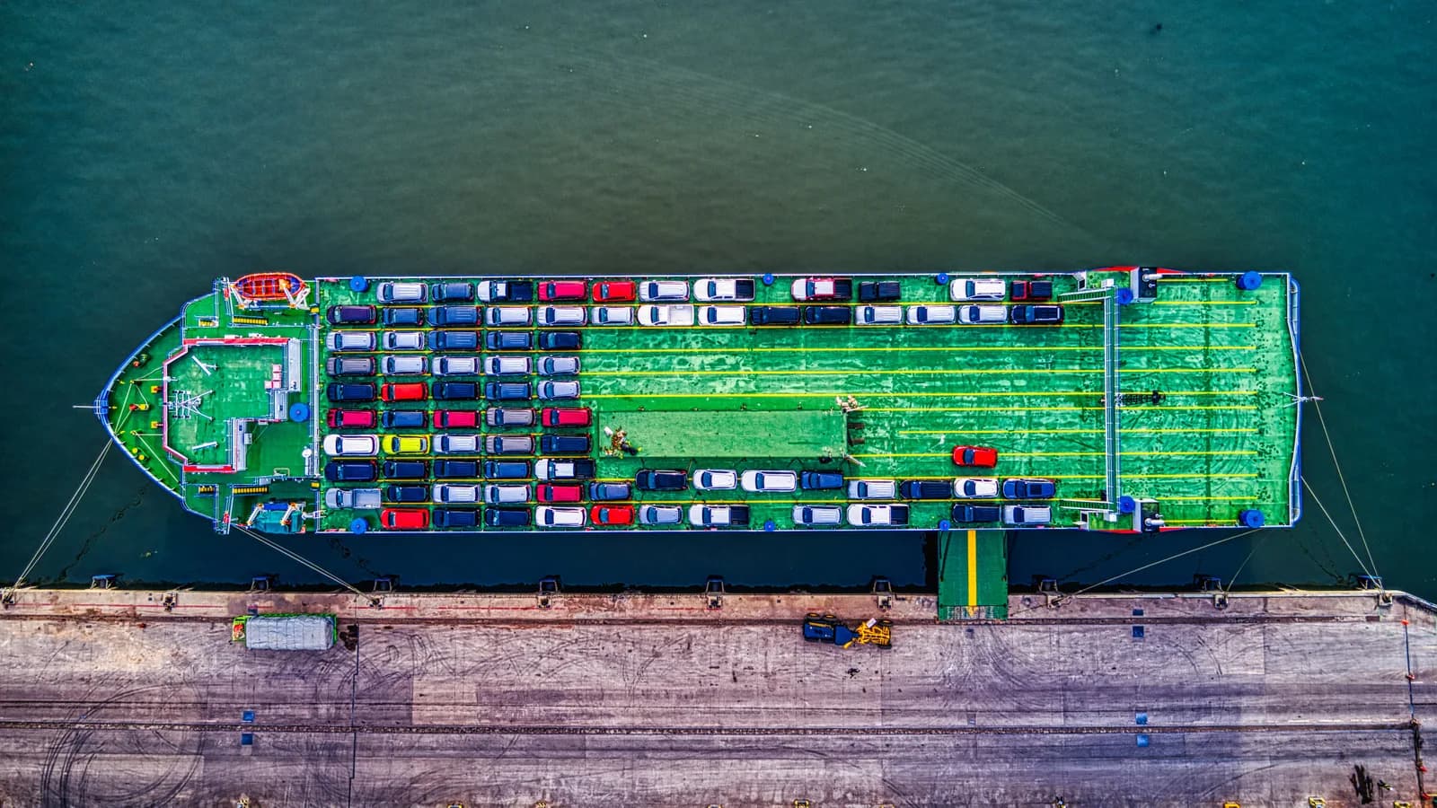 Car carrier ship tied up at a wharf with vehicles packed across its decks