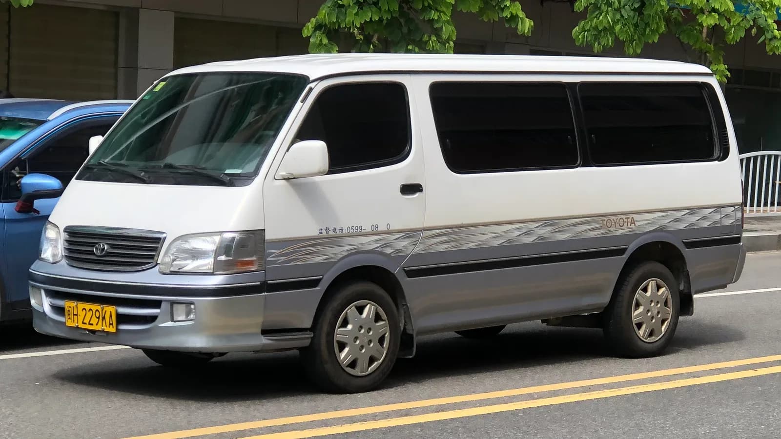 A white and grey Toyota HiAce van parked on a street, unconverted