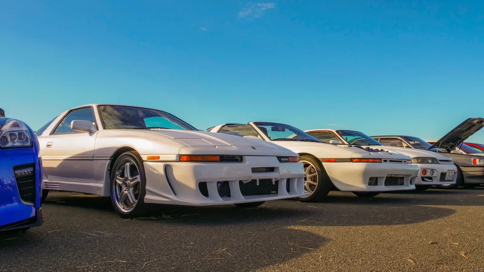 Several Japanese sports cars lined up in a dealer-style outdoor lot