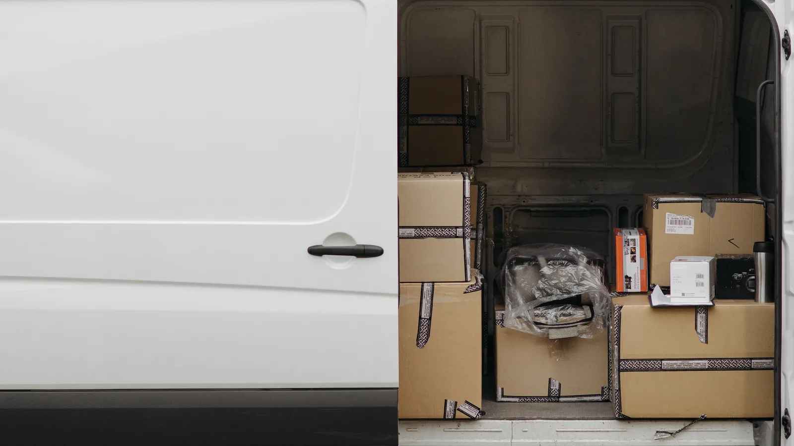 The rear cargo area of a van packed with taped cardboard boxes