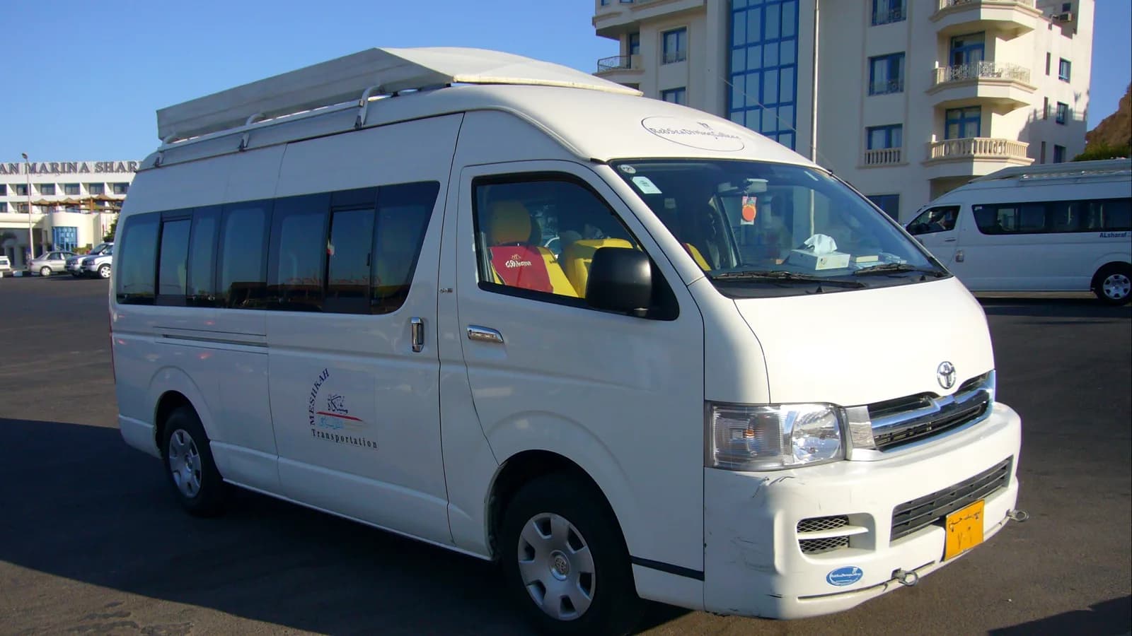 A white Toyota HiAce with a pop-top camper roof parked at the kerb in a suburban street