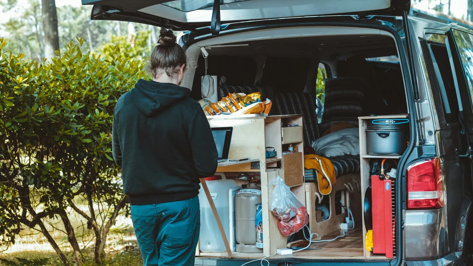 Camper builder working beside a plywood kitchen unit in the rear of a van