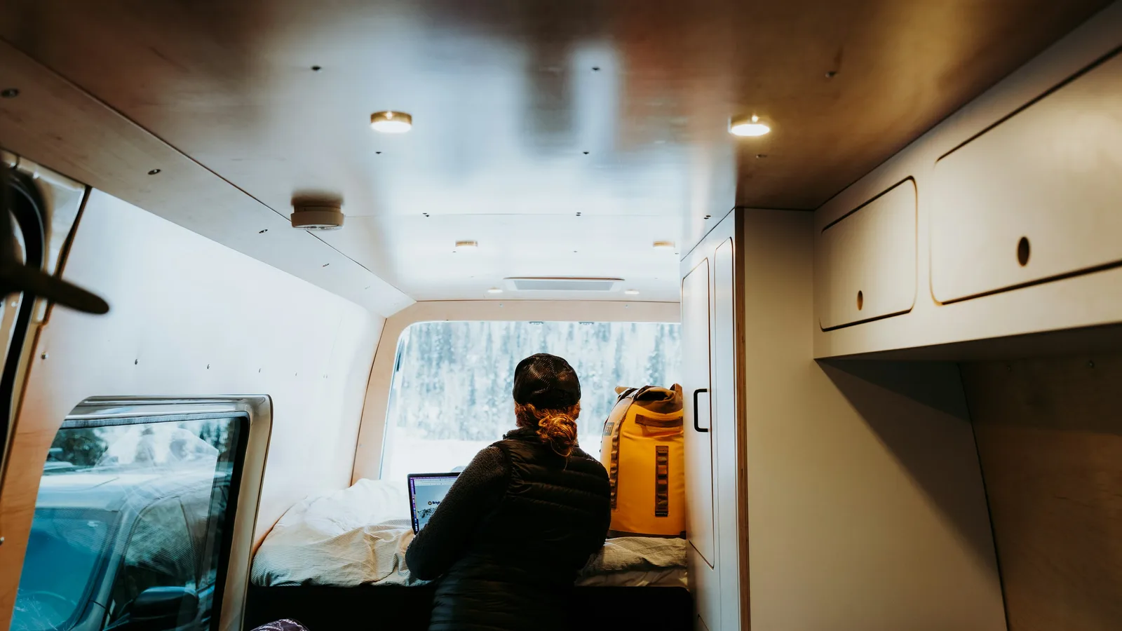 Completed plywood camper interior with a bed, cupboards and ceiling lights
