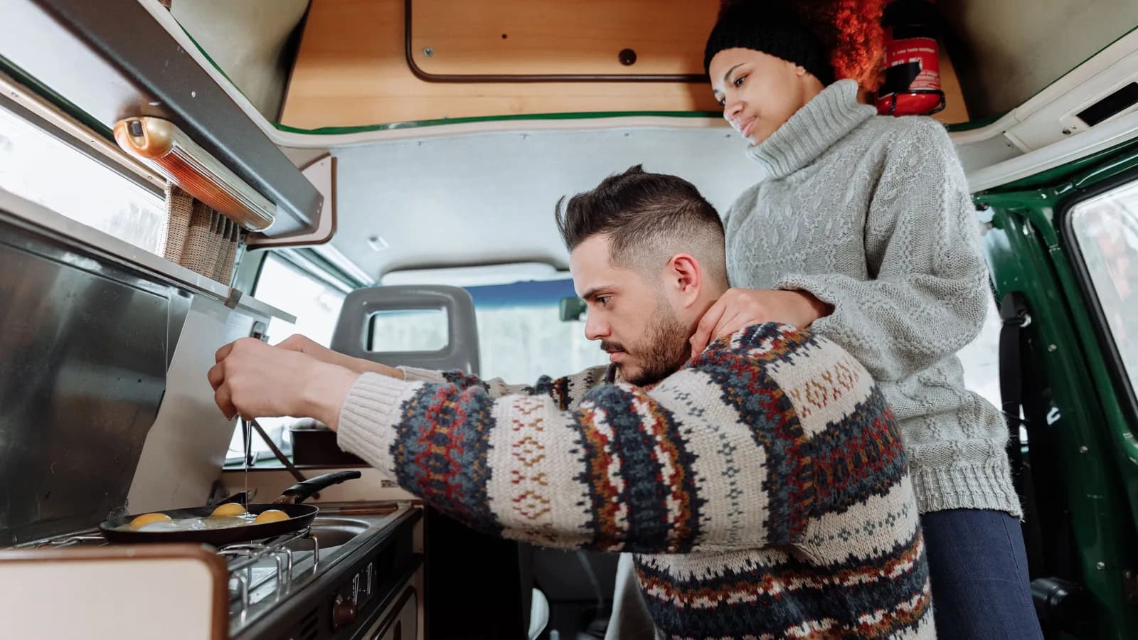 Couple cooking at the fitted gas hob inside a finished campervan