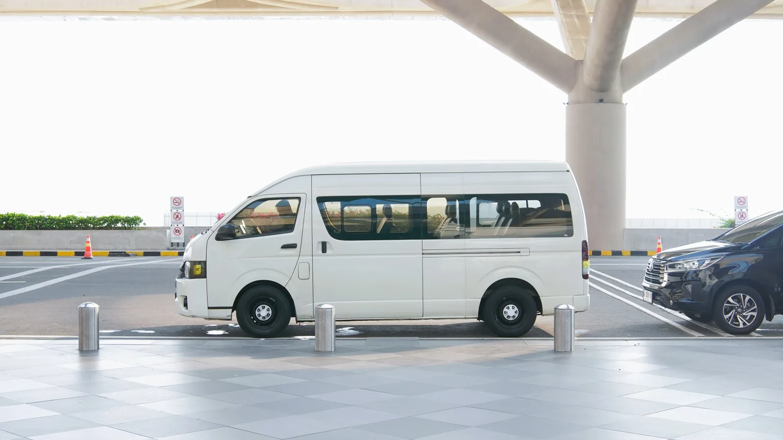 A white Toyota HiAce van parked in profile under a covered canopy