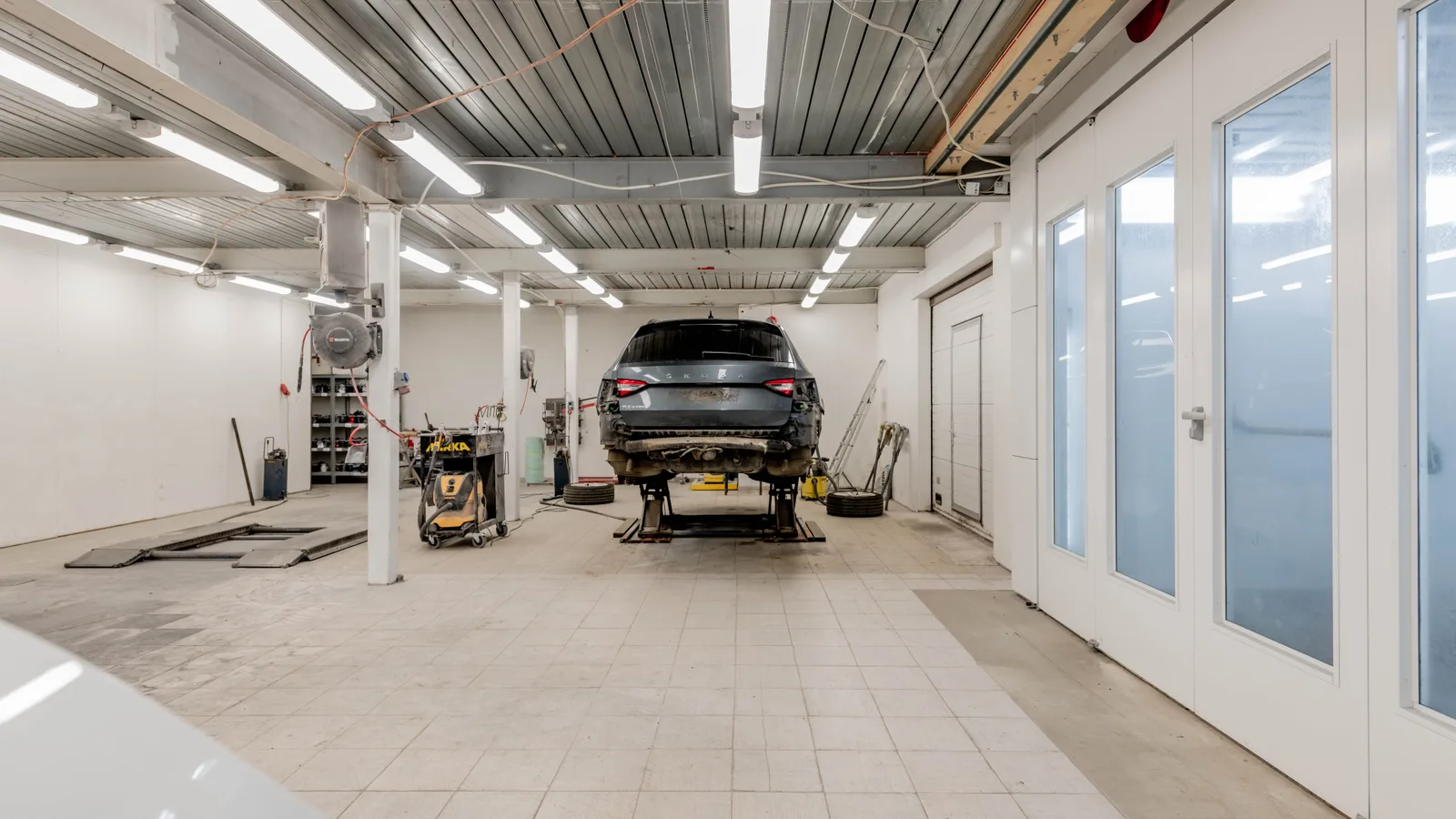 An SUV raised on a workshop hoist in a clean service bay, viewed from behind