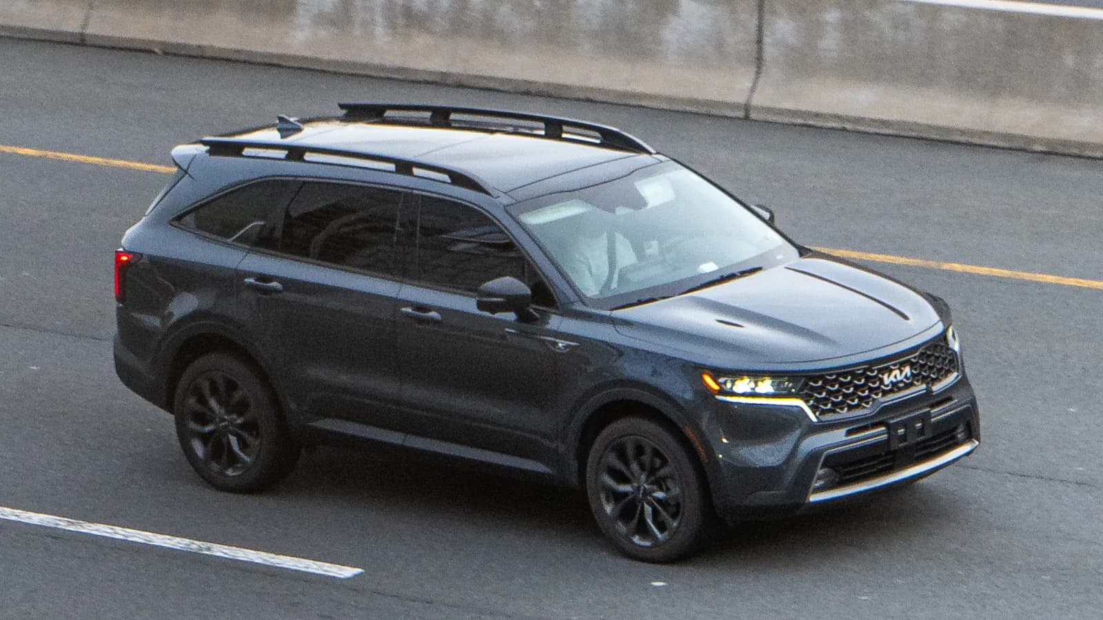 A dark grey Kia Sorento travelling along a multi-lane highway