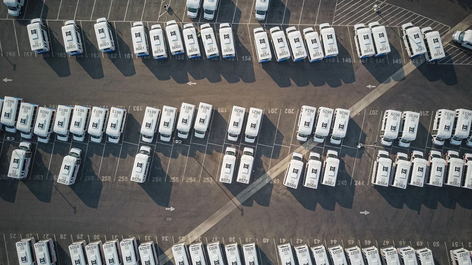 Numbered parking bays in a fleet yard filled with identical white vans