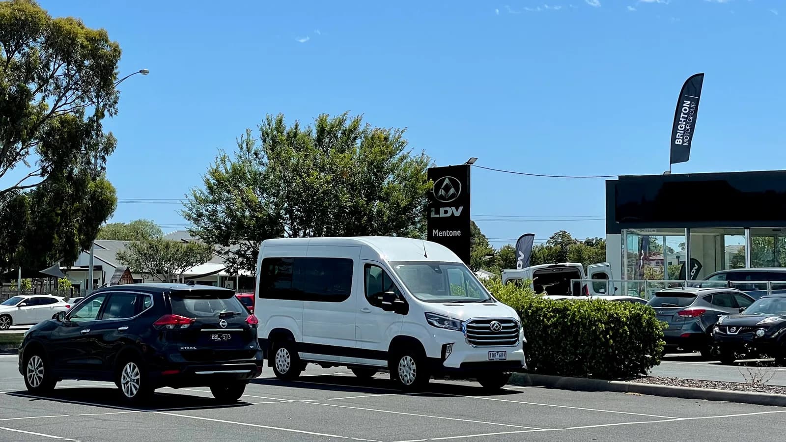 A white LDV Deliver 9 van parked beside an LDV dealership sign