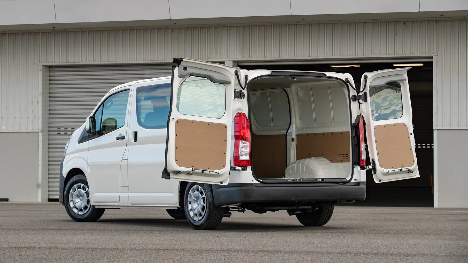 The open rear doors of a white HiAce showing a bare, unlined cargo area