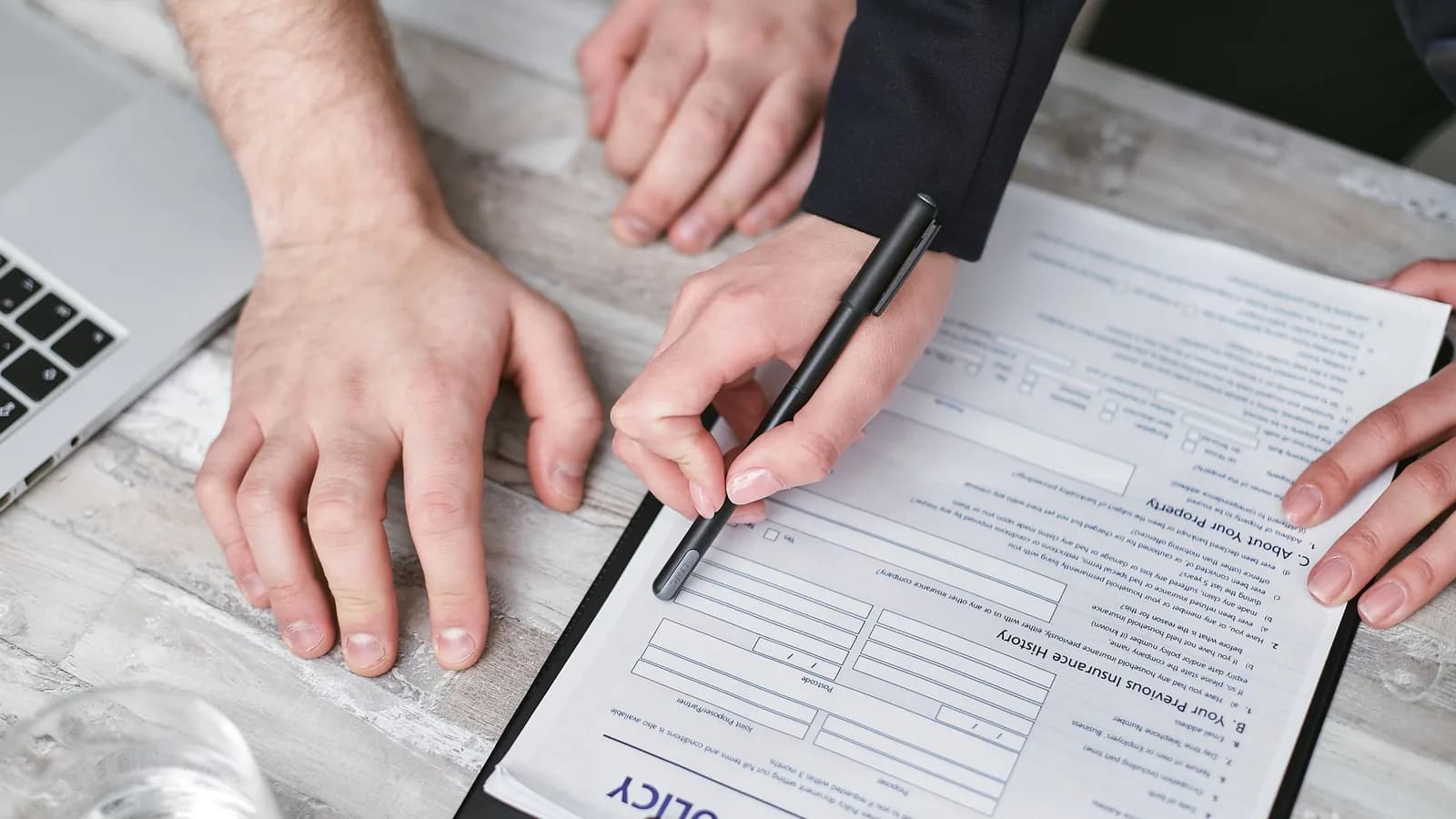 Two people at a desk reading and signing an insurance policy document