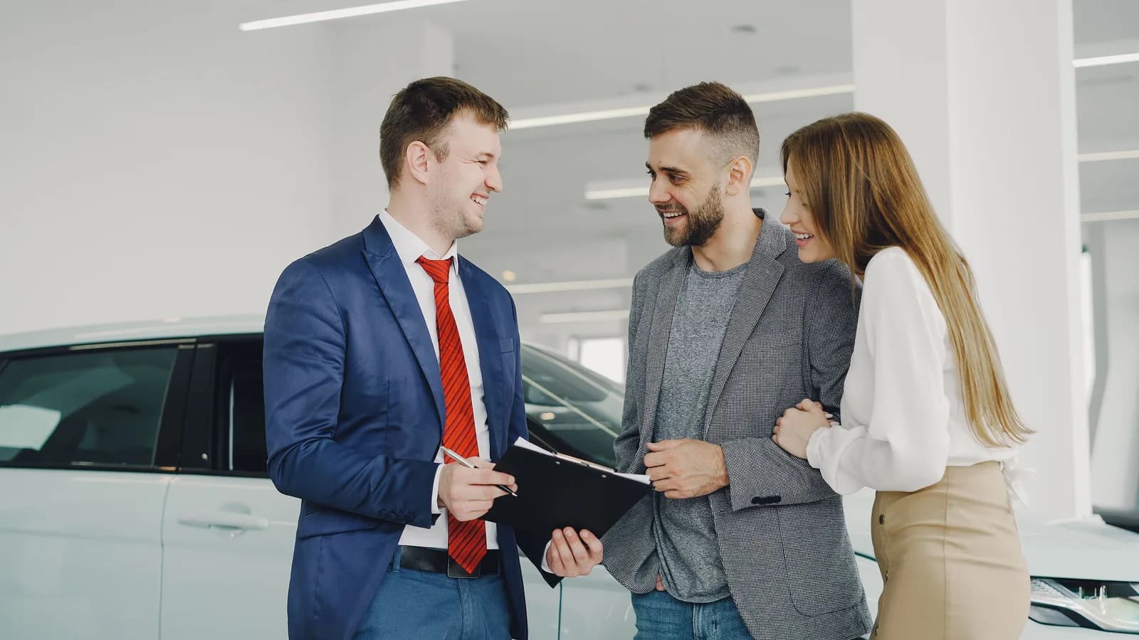 A couple reviewing vehicle paperwork with a car dealer