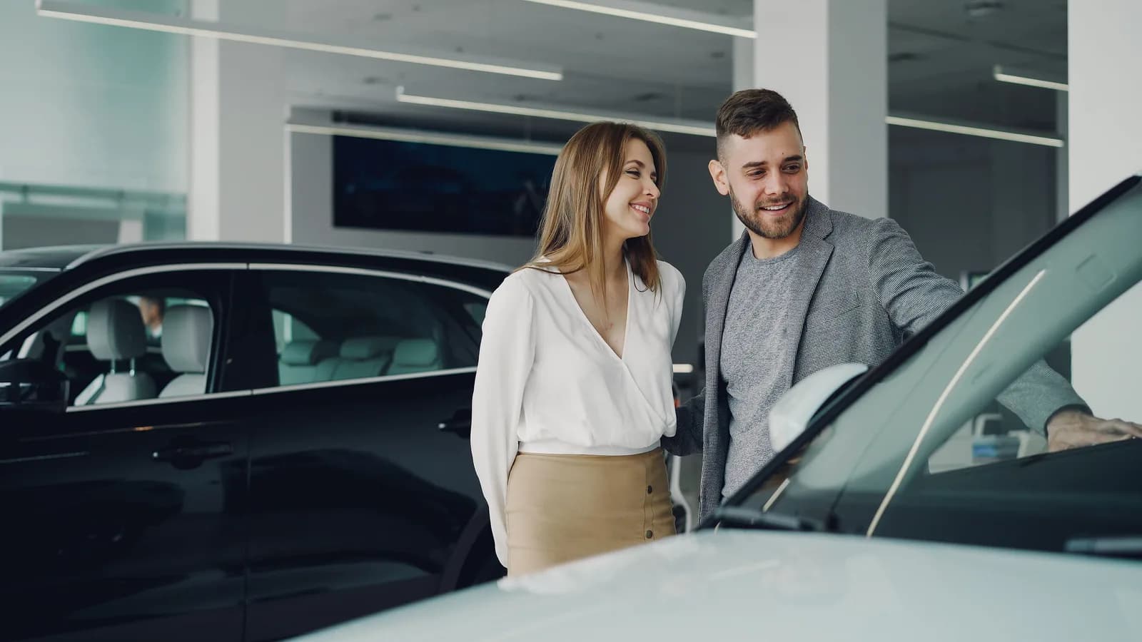 A couple speaking with a salesperson beside a black SUV in a dealership