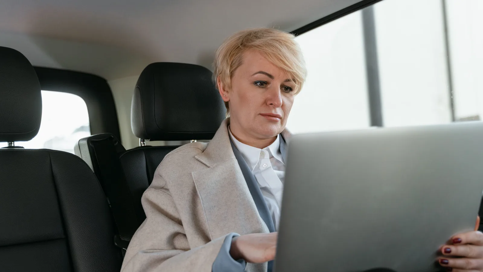 A woman with short hair working at a laptop inside a vehicle