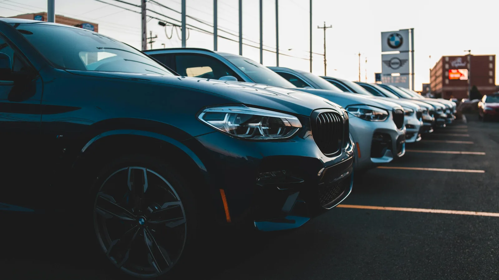 Rows of SUVs parked on a dealership lot with signage behind them
