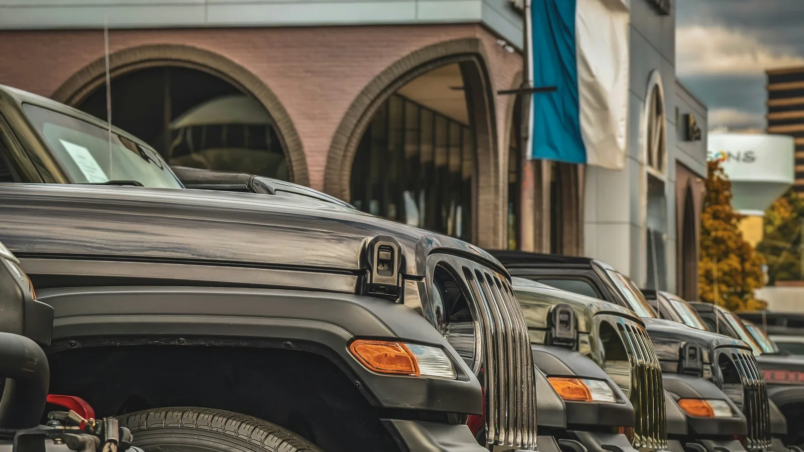 A row of SUVs parked outside a used car dealership showroom