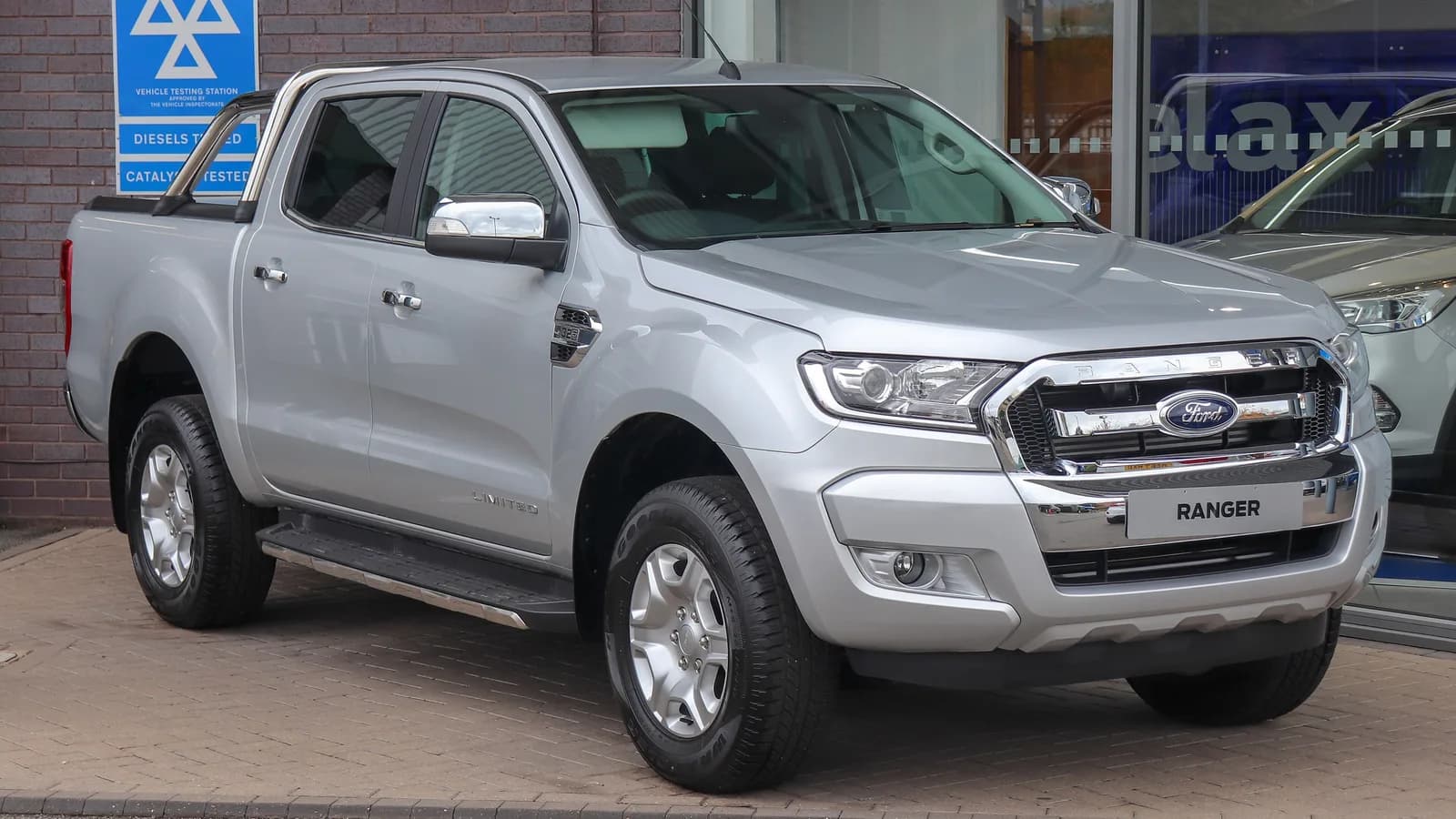 Silver Ford Ranger dual-cab ute parked outside a dealership, seen from the front three-quarter angle