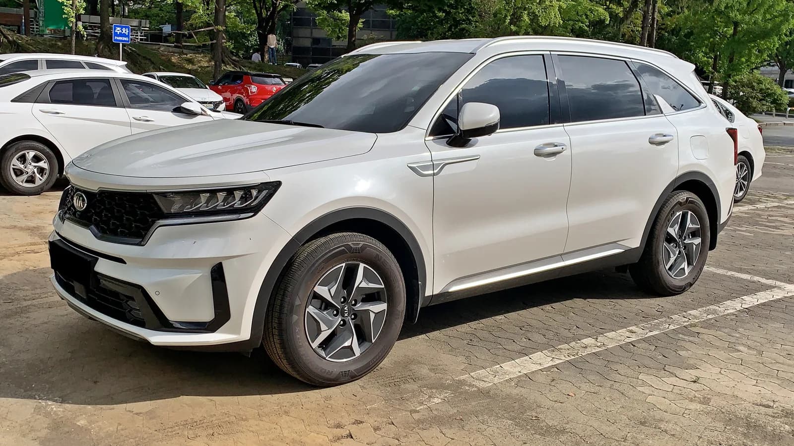 A white Kia Sorento seven-seat SUV parked in a car park, seen from the front three-quarter angle